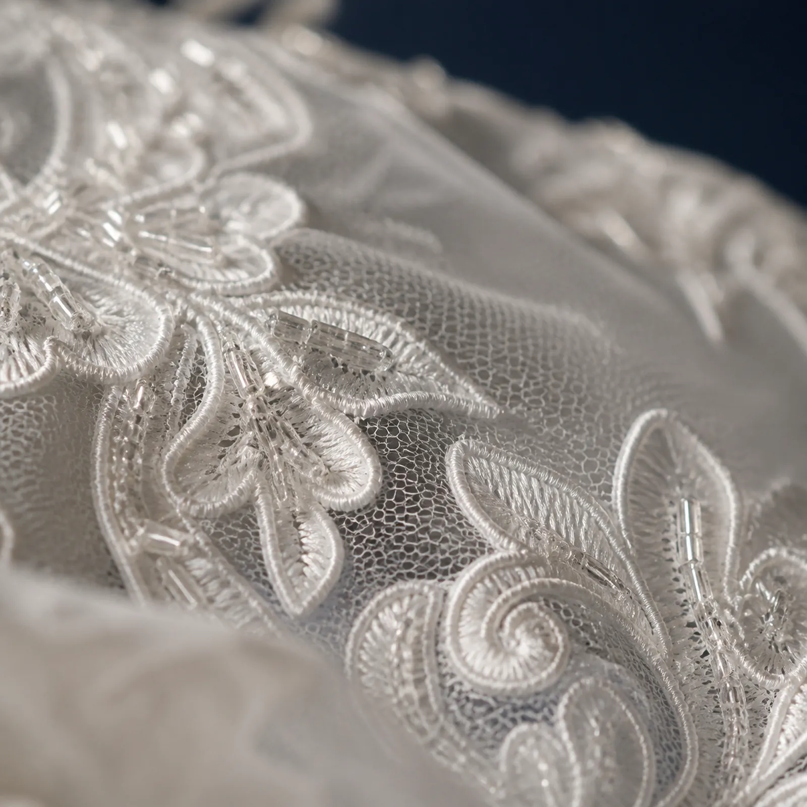 Dettaglio ravvicinato di pizzo e ricami su un tessuto da sposa